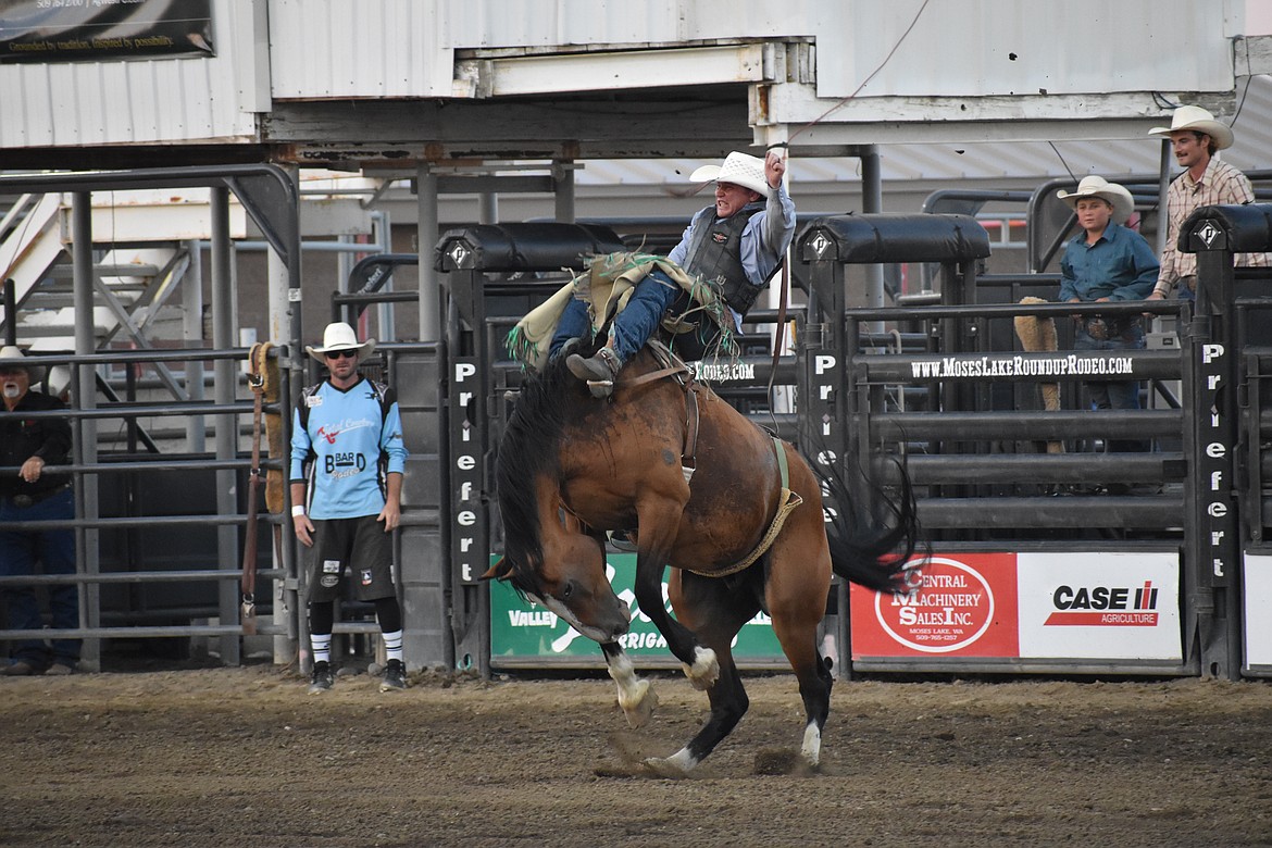 Bareback rider Joshua Dollins raises his arm while staying atop his horse at Friday’s Moses Lake Roundup.