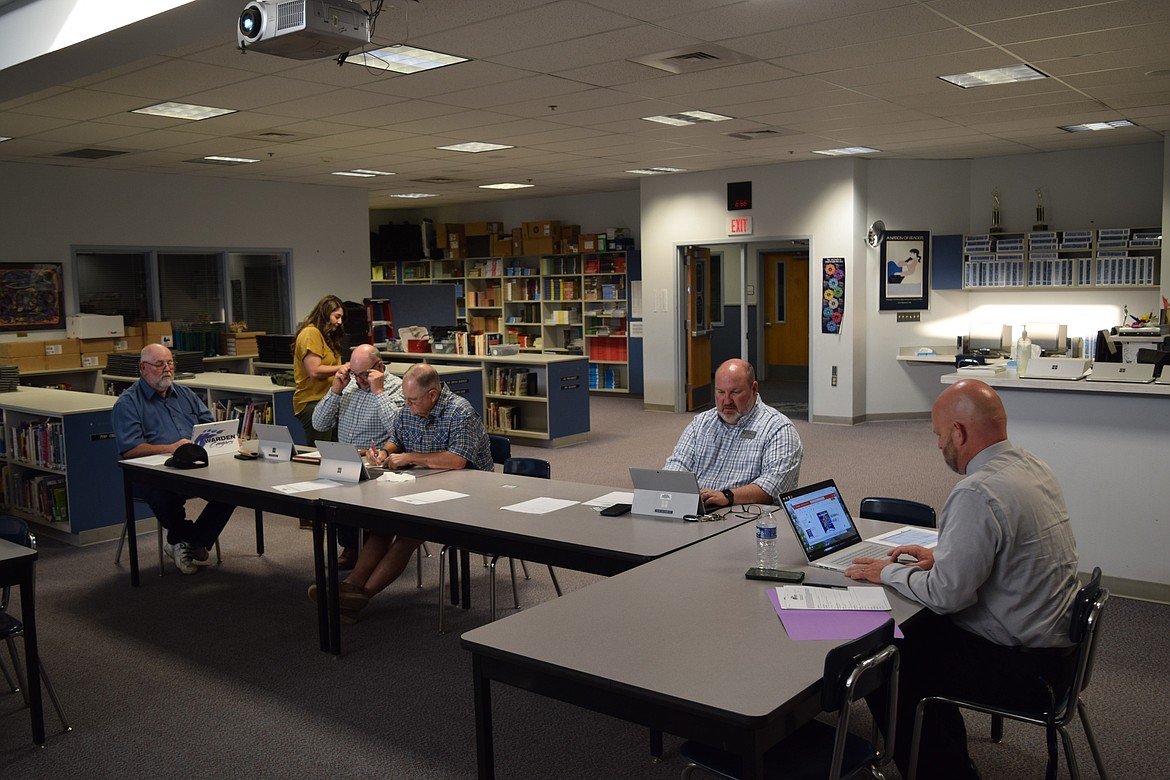 Members of the Warden School Board look over the agenda during Thursday’s school board meeting at Warden High School. The board approved a contract to supply milk to the district during the meeting.