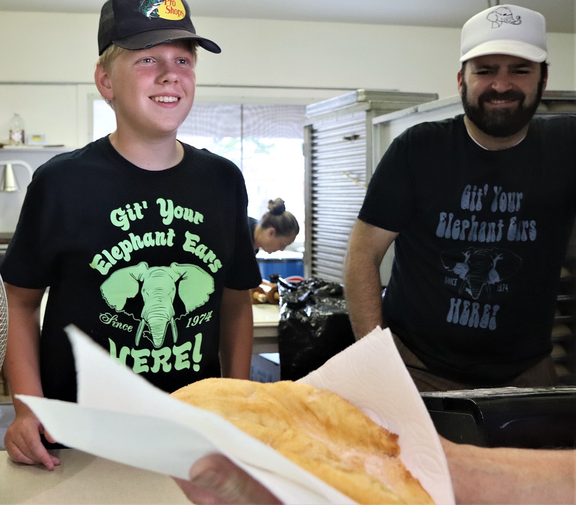 Rowdy Carr smiles after giving a customer his elephant ear while Blair Davis looks on during the North Idaho State Fair on Saturday.