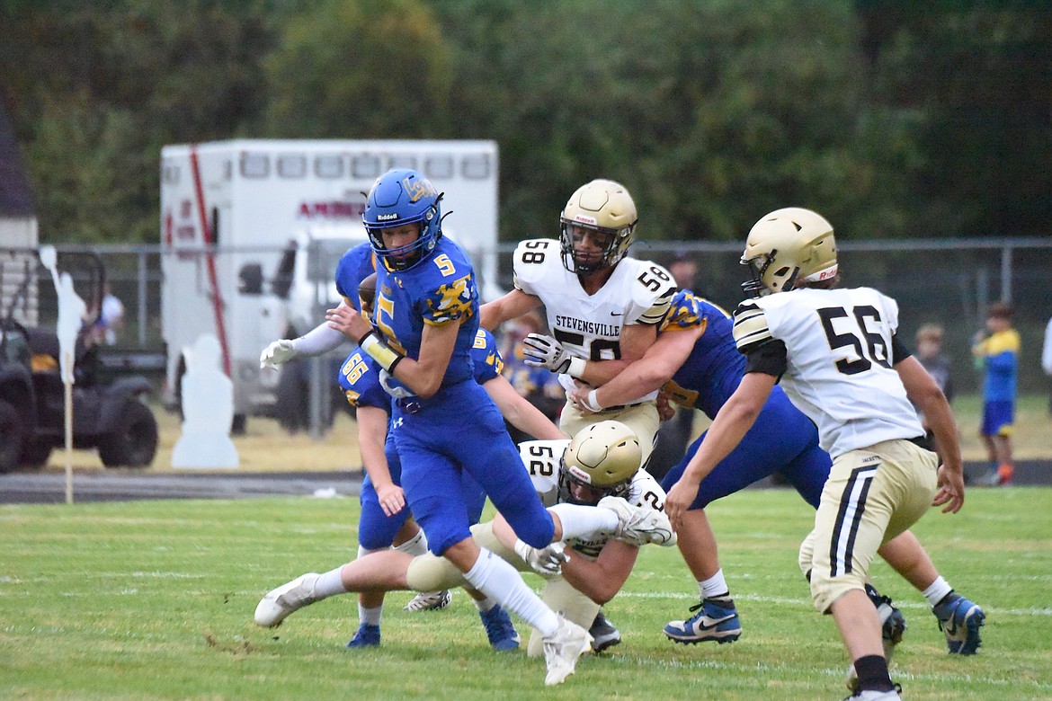 Libby quarterback Tristan Andersen runs out of a tackle attempt by a Stevensville defender in Friday's game. (Scott Shindledecker/The Western News)