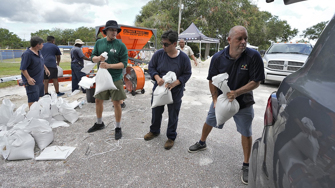 Members of the Tampa, Fla., Parks and Recreation Dept., help residents load sandbags Monday, Aug. 28, 2023, in Tampa, Fla. Residents along Florida's gulf coast are making preparations for the effects of Tropical Storm Idalia. (AP Photo/Chris O'Meara)