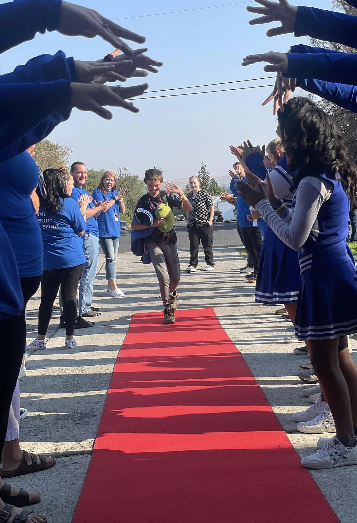 A Soap Lake Middle/High School student walks on the red carpet while cheerleaders and staff cheer on Monday, the first day of school in the Soap Lake School District.