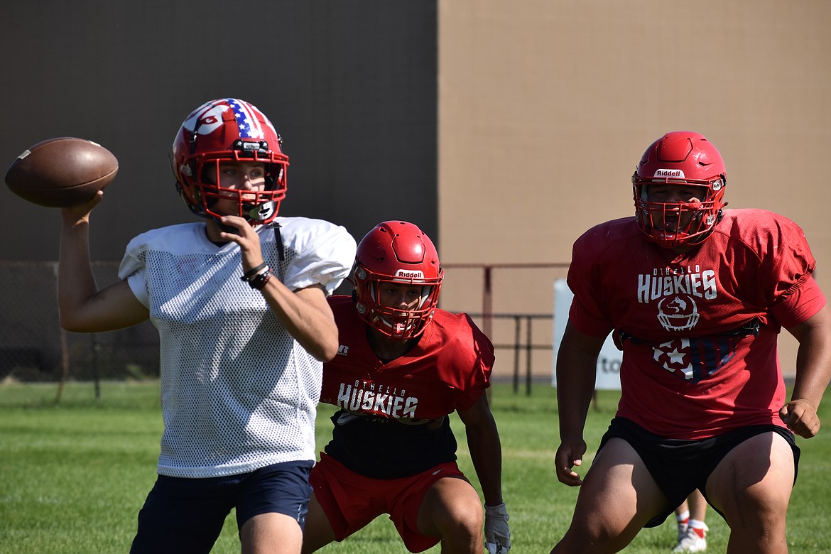 Othello defenders, in red, look toward a quarterback during a pursuit drill on a practice on Friday.