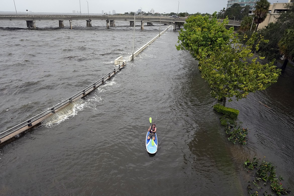 Flood waters pushed by Hurricane Idalia pour over the sea wall along Old Tampa Bay as paddle boarder Zeke Pierce, of Tampa, rides Wednesday, Aug. 30, 2023, in Tampa, Fla. (AP Photo/Chris O'Meara)