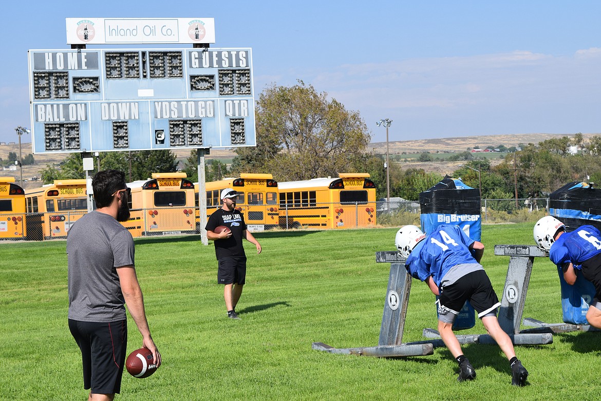 Soap Lake Football Head Coach Garrett Devine, middle, oversees football practice with one of his assistant coaches, left. Under the newly approved Collective Bargaining Agreement, Devine and other coaches who are not otherwise employed by the school district are given a full contract with a specified base pay of approximately $52,000