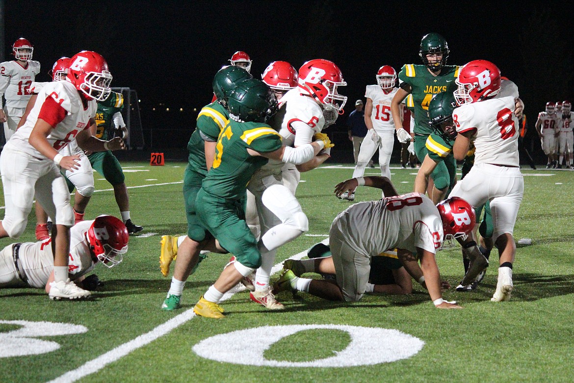 Quincy defenders wrap up a Brewster running back during a 2022 game.