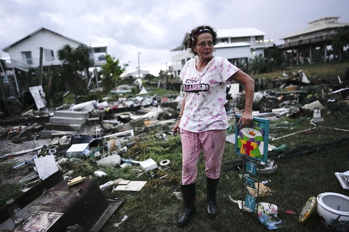 Jewell Baggett stands beside a Christmas decoration she recovered from the wreckage of her mother’s home, as she searches for anything salvageable from the trailer home her grandfather had acquired in 1973 and built multiple additions on to over the decades, in Horseshoe Beach, Fla., after the passage of Hurricane Idalia, Wednesday, Aug. 30, 2023. (AP Photo/Rebecca Blackwell)