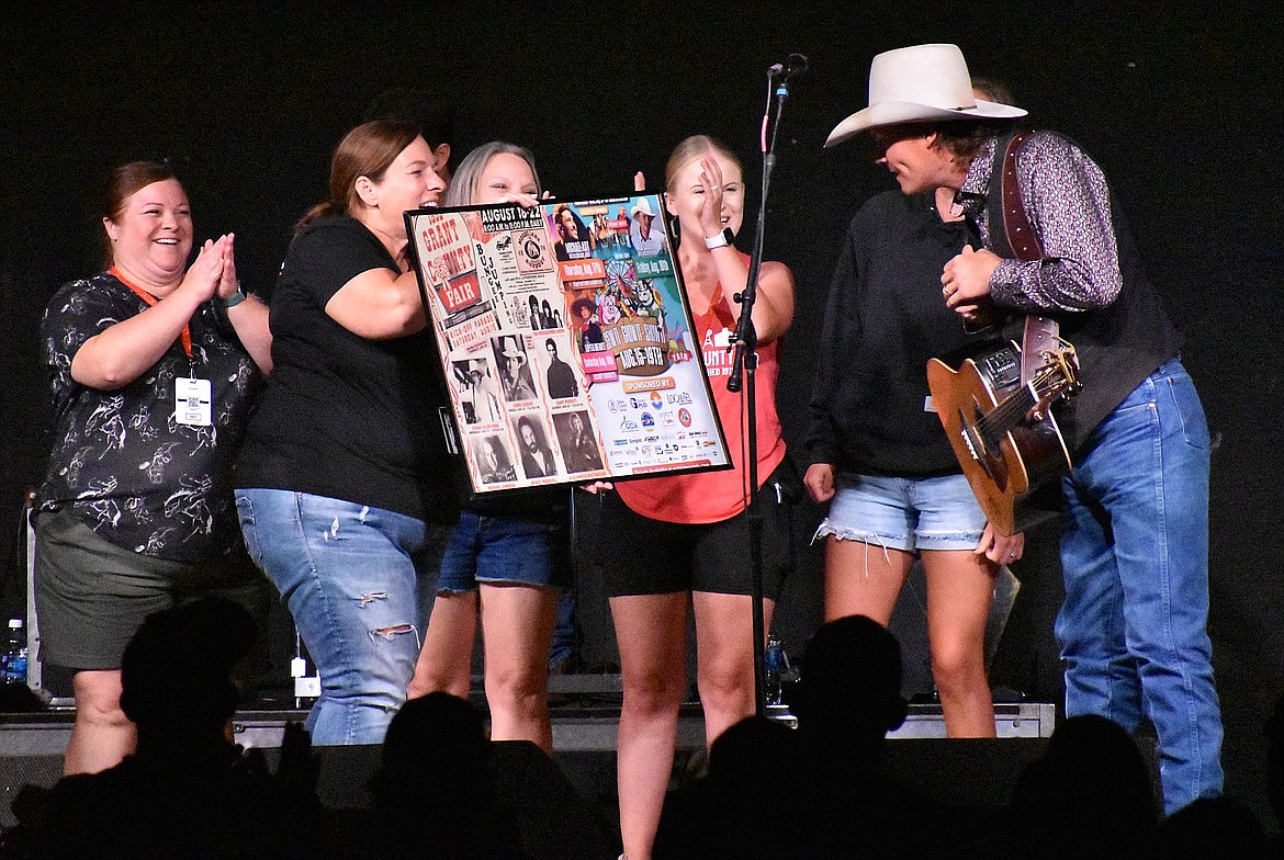 Grant County Fairgrounds staffer Darci Homesley presents Ned LeDoux with a framed copy of the fair posters from his performance and his father’s, 31 years earlier to the day.