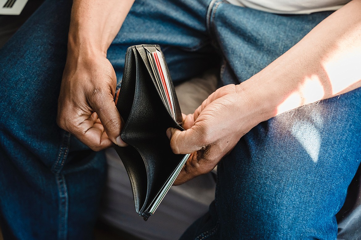 Person looking in empty wallet for money while wearing blue jeans