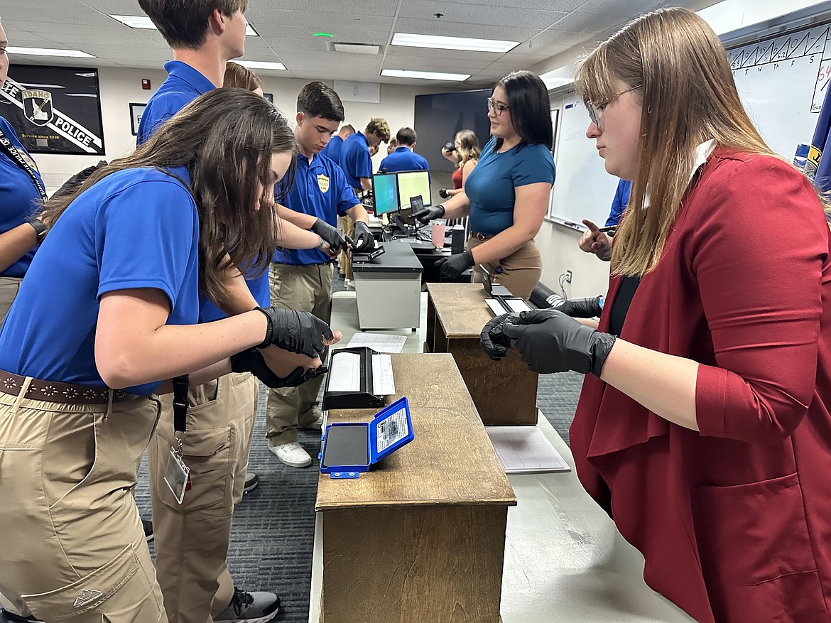 Charity Partridge, left, tries her hand at fingerprinting during ISP Leadership Education & Development Academy, held in late June.