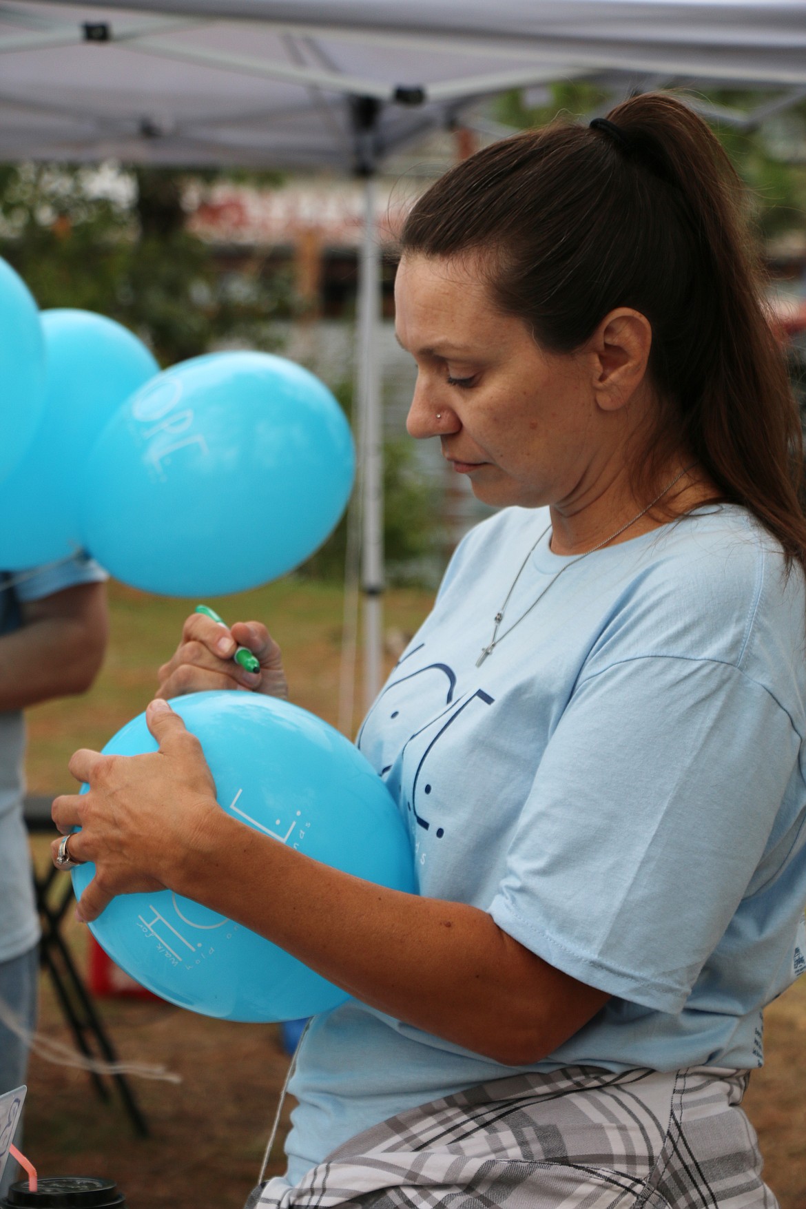 A participant in the 2023 Walk for HOPE writes a message on a balloon during Sunday's annual event that aims to call attention to suicide awareness.