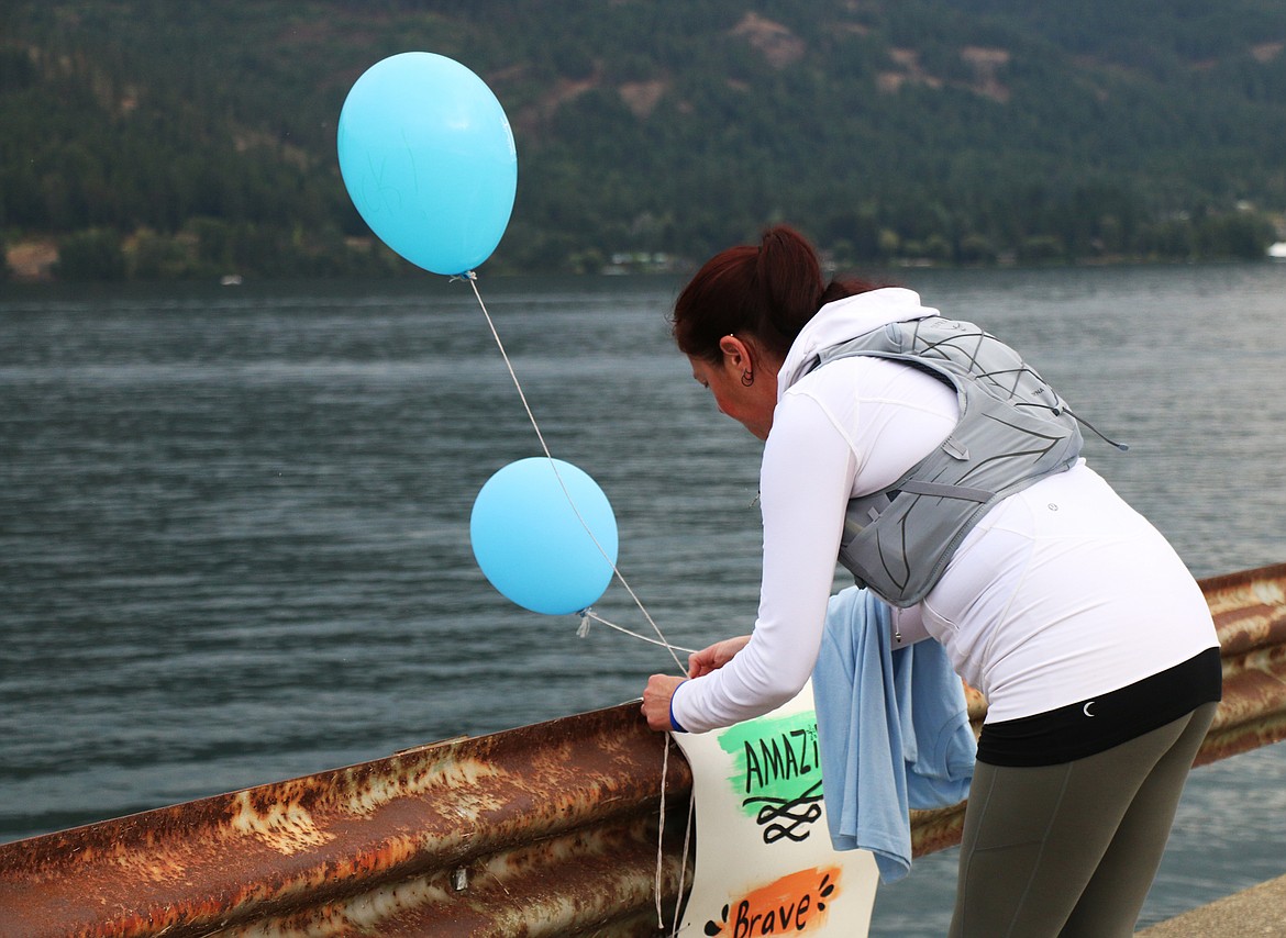 A Walk for HOPE participants ties a balloon to one of the signs adorning the Long Bridge during the 2023 event.