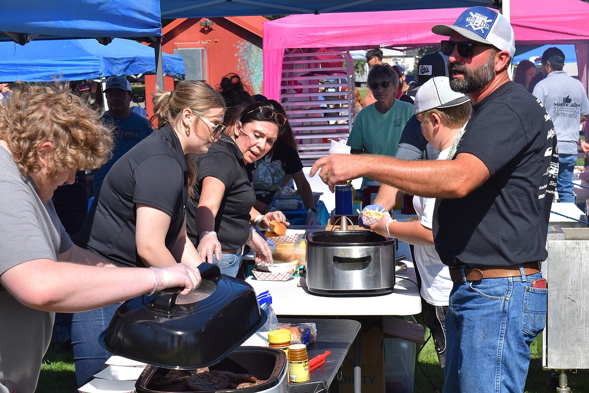 Warden Community Days volunteers prepare and serve food to the community in Volunteer Park Monday afternoon.