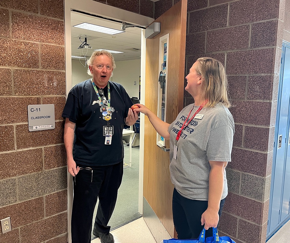 Trustee Heather Tenbrink surprises Lake City High School computer technology teacher Scott Jacobson with an apple Tuesday morning. Delivering apples to teachers on the first day of the school year is a longstanding tradition for trustees of the Coeur d'Alene School District.