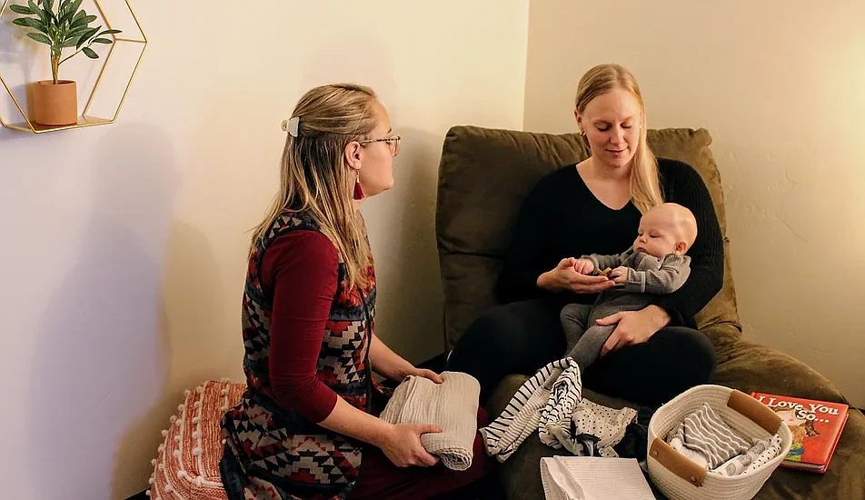 A doula with the Postpartum Resource Group sits with a new mom. (photo provided)