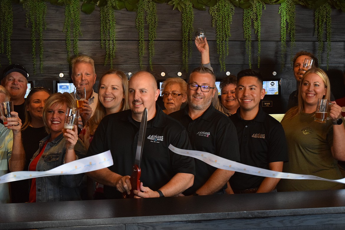 Michael’s Bistro co-owner Michael Stevens cuts the ribbon unveiling the restaurant's new PourMyBeer self-pour beer tap and dispensing system Wednesday evening while other co-owners, employees, friends and family raise their glasses to mark the occasion.