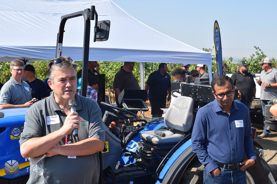 Tory Schmidt, left, with the Washington Tree Fruit Research Commission, presents on chemical spray applications to field day attendees while WSU Professor Lav Khot, right, listens.