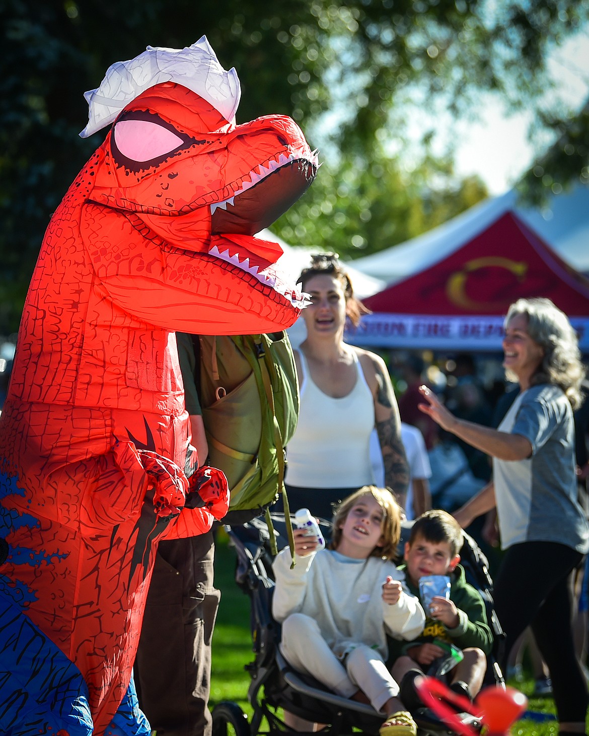 Kids smile at a costumed Tyrannosaurus rex at the Whitefish Community Foundation's Great Fish Fun Run in Whitefish on Saturday, Sept. 9. (Casey Kreider/Daily Inter Lake)