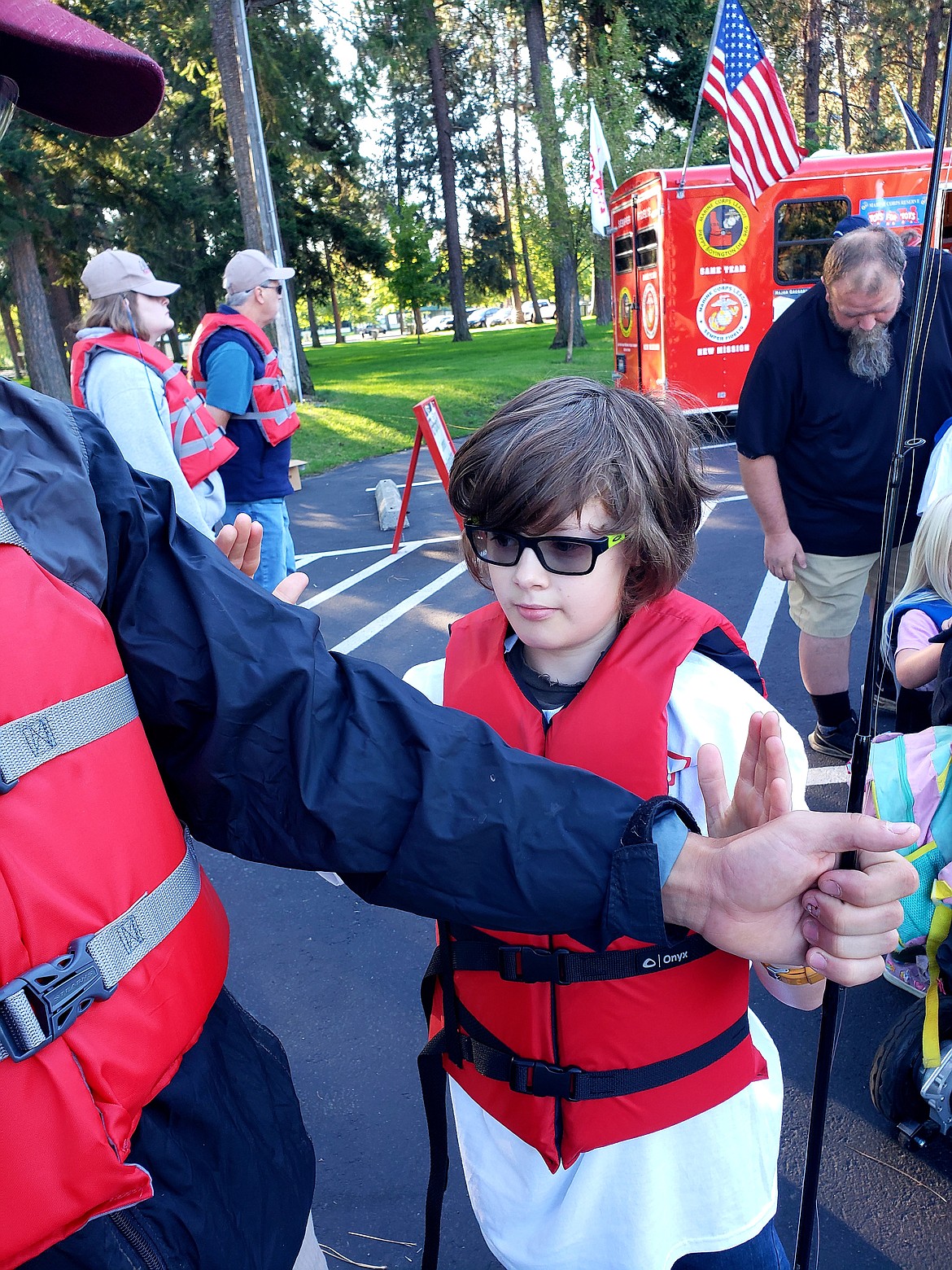 Tanner Sams, 12, illustrates how big a "monster fish" is on his friend's arm before heading to the water for a C.A.S.T for Kids day of fishing.