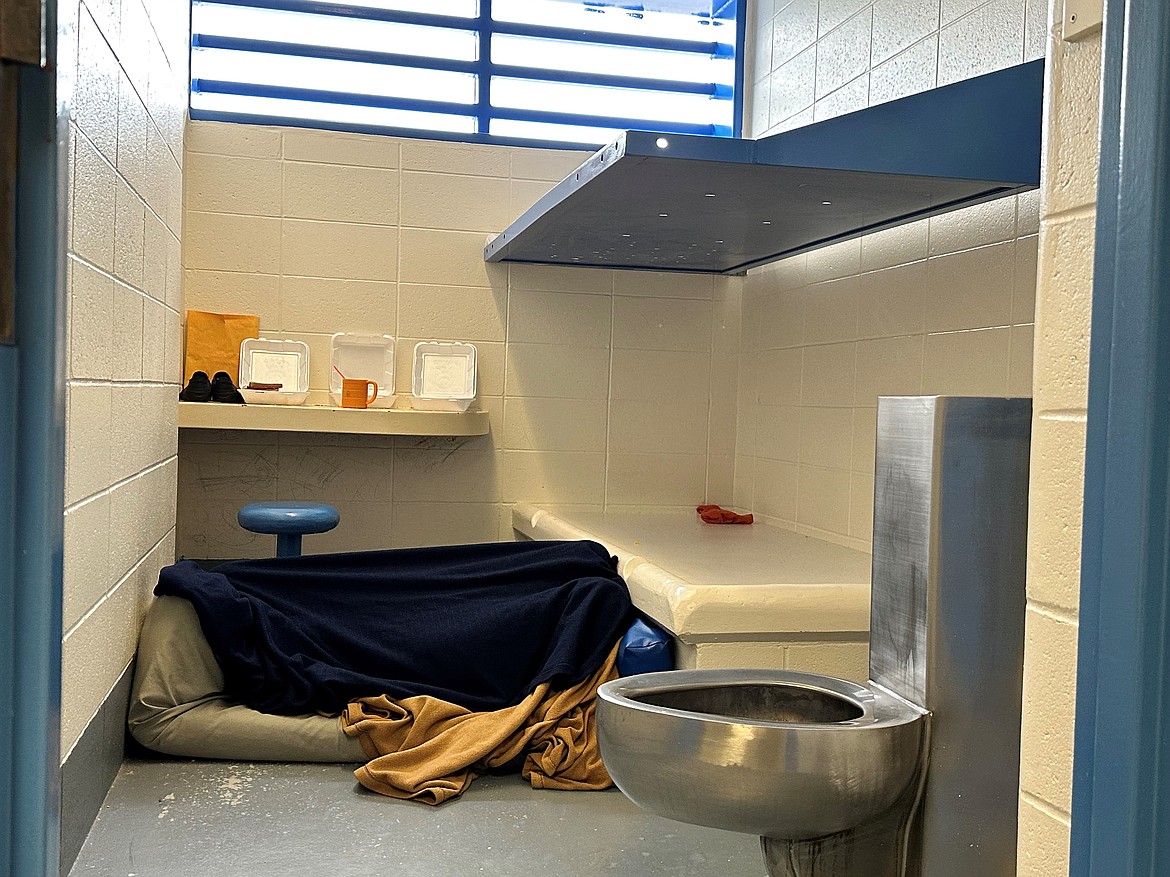 An unidentified woman lies under a blanket in a cell in the Flathead County Detention Center in Kalispell, Montana. She has been held there for nearly a year after being found mentally unfit to stand trial on burglary charges, a jail official said. (Aaron Bolton/KFF Health News)