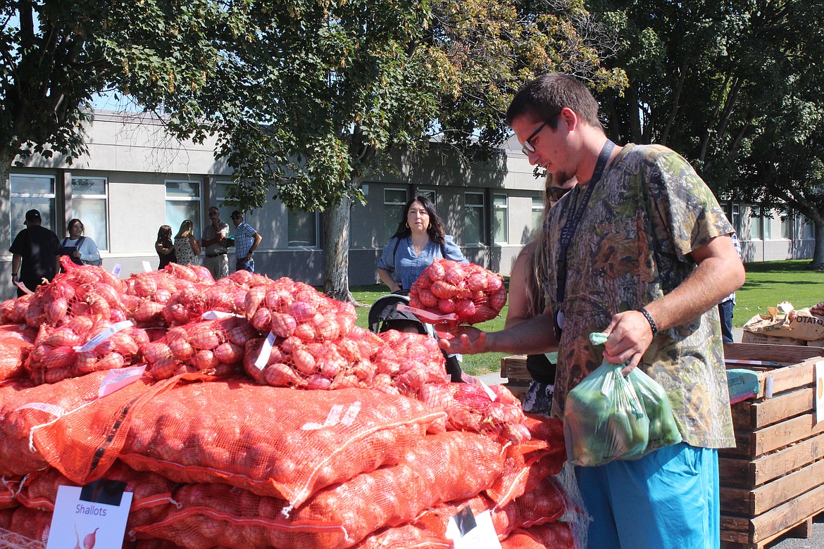 A shopper checks out the pallet of shallots at the Quincy High School Future Farmers of America produce sale during Farmer Consumer Awareness Day.