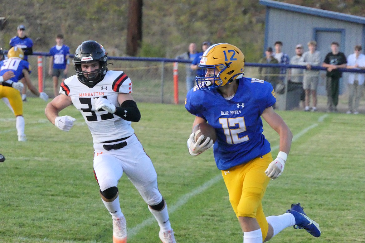 Blue Hawks senior running back Nick Tessier runs past a would-be Manhattan tackler during their game Friday night in Thompson Falls.  (Chuck Bandel/VP-MI)