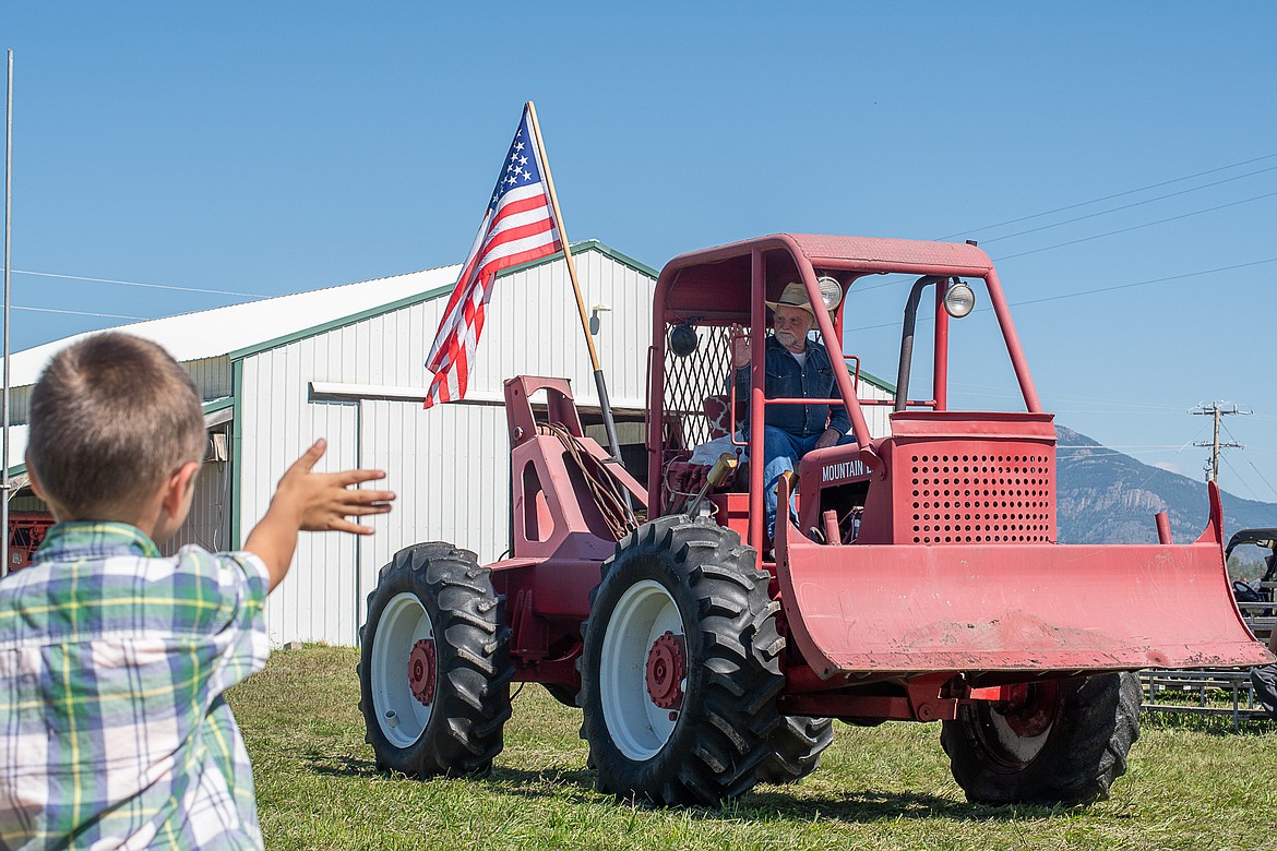 A youngster waves to Tex Manus in the tractor parade on Sept. 10.