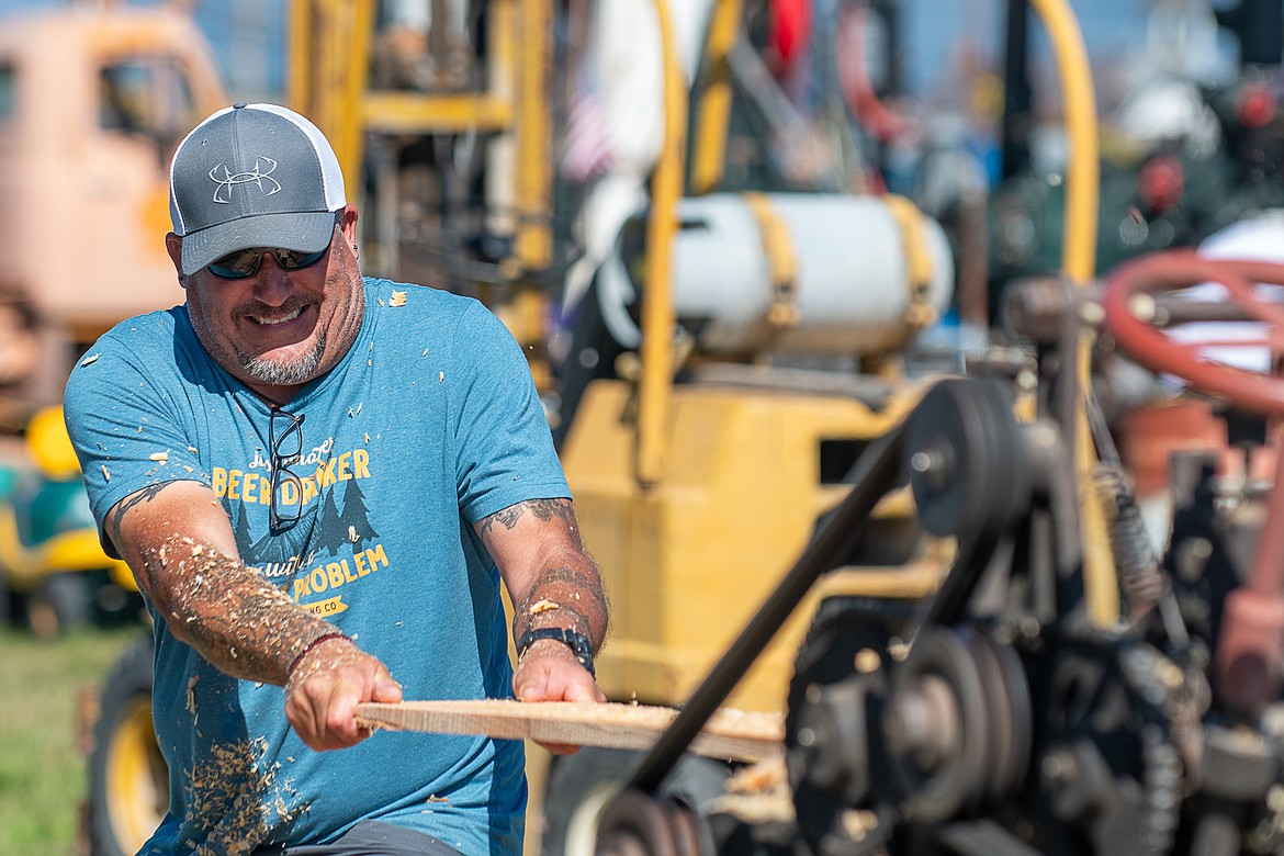 Tim Sayers yanks a fresh board from an antique planer on Sept. 10.