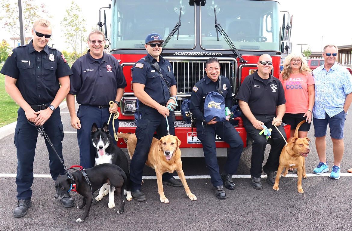 Northern Lakes Fire District personnel and Jamie and Andy Smith pose with dogs at Companions Animal Center on Tuesday. From left, Austin Winters, Chris Larson, Jason Paulson, Jarrod Pitts, Tyler Drechsel, and Jamie and Andy Smith.