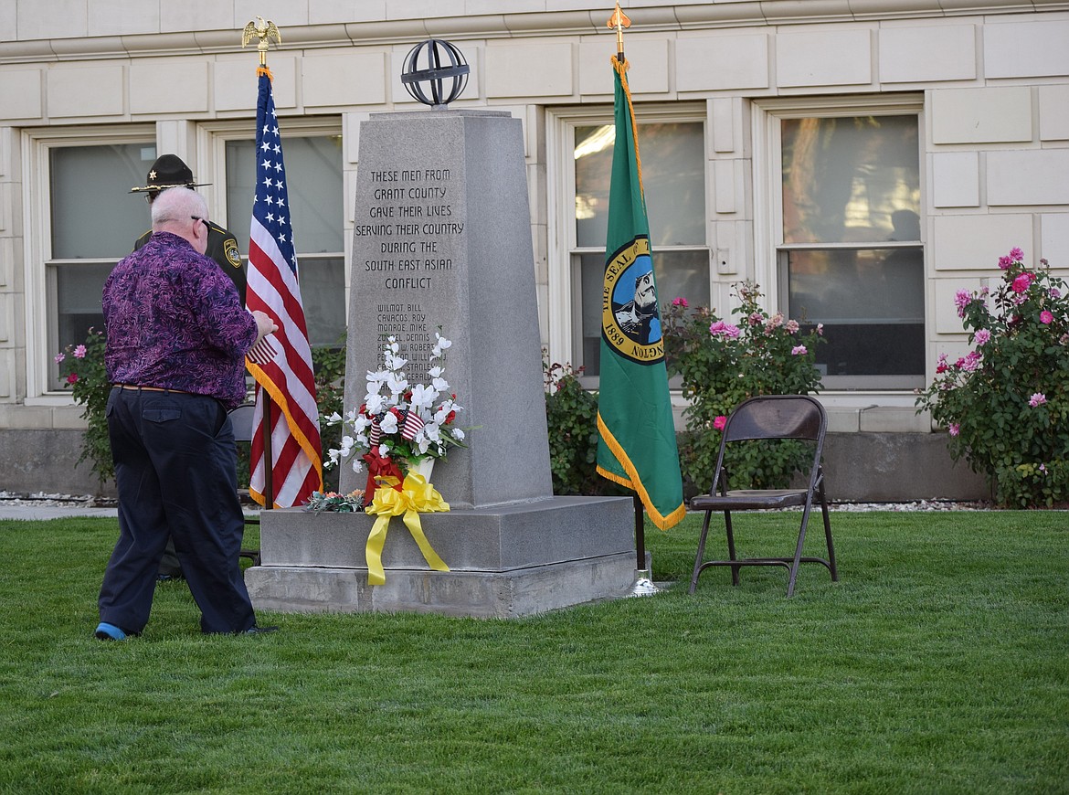 Ephrata Mayor Bruce Reim places a flag in a vase in honor of those who served in the military during one of the United States’ seven major military conflicts. The memorial the vase is positioned on lists the names of Grant County service members who were killed during the Vietnam War.