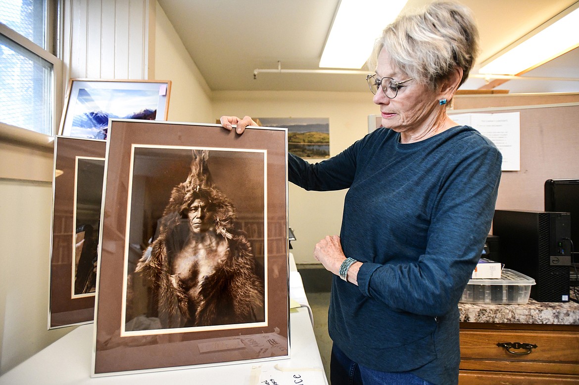 Terri Hill, a volunteer and the yard sale coordinator at the Northwest Montana History Museum, displays two framed prints by photographer Ed Gilliland on Wednesday, Sept. 13 that will be up for sale during the museum's yard sale. (Casey Kreider/Daily Inter Lake)