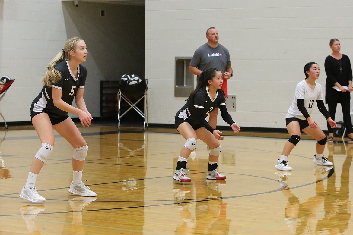 The Warrior back row of senior Kayleigh Elder (5), senior Beth Okamoto (2) and freshman Grace Okamoto (17) await a serve by Waterville-Mansfield on Saturday.