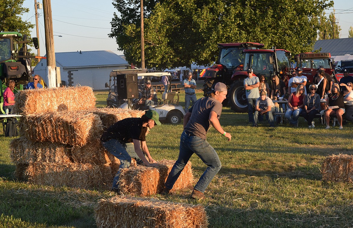 A team of two competes in the 2023 Othello Fair Hay Bucking Contest. The goal of the contest is for one team member to stack hay bales while the other carries them, as quickly as possible.