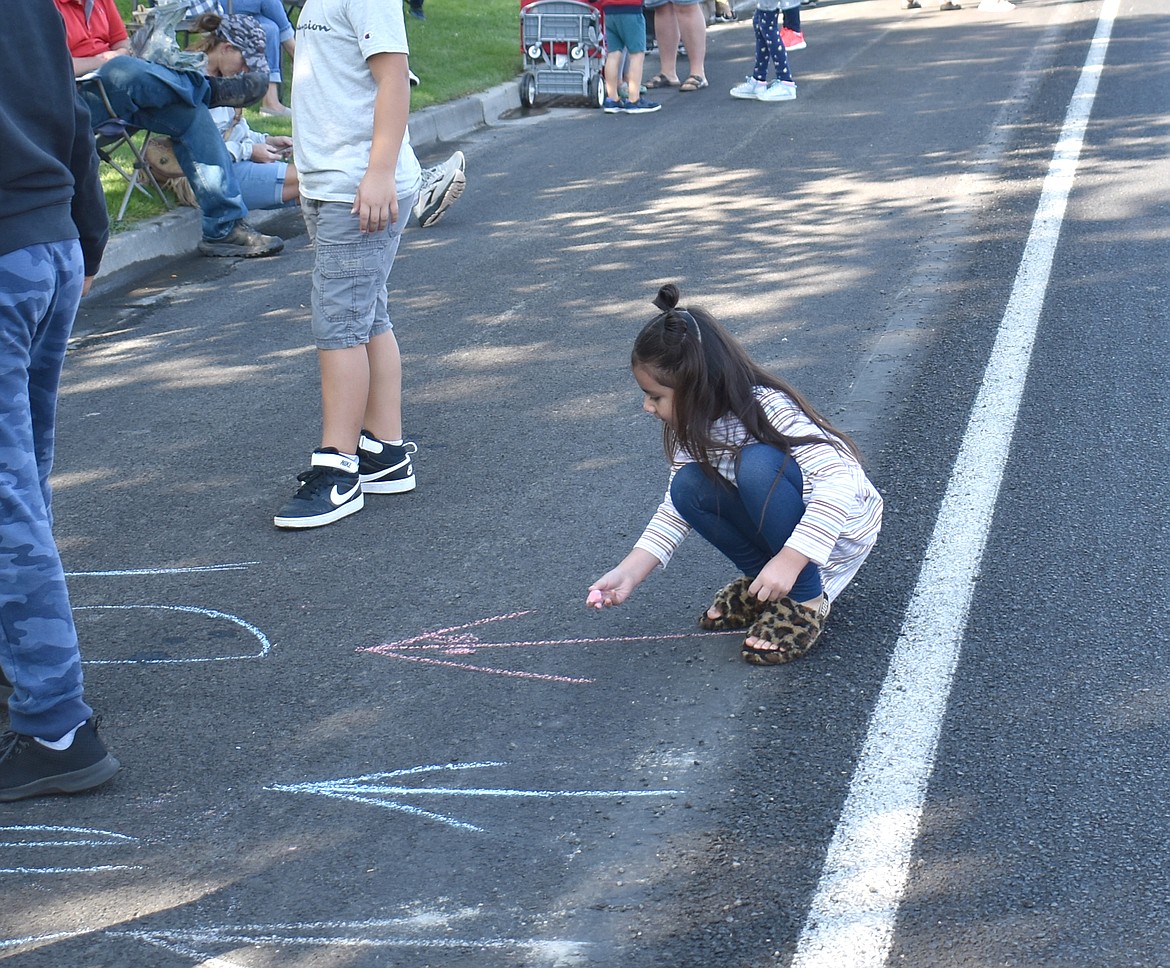 Four-year-old Melanie Spencer of Othello gets in a little artwork before the Othello Parade Saturday.