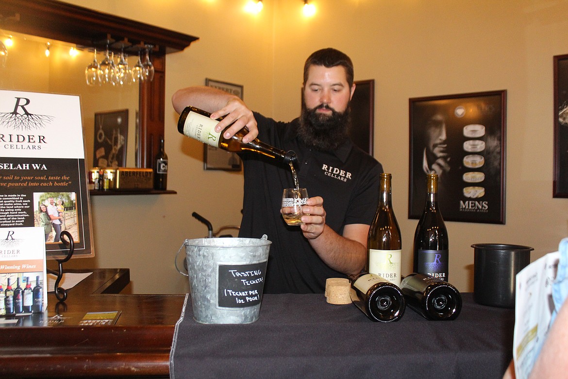 Colby Rider of Rider Cellars pours out the wine during the Sip ‘n Stroll art, music and wine walk sponsored by the Downtown Moses Lake Association Saturday.