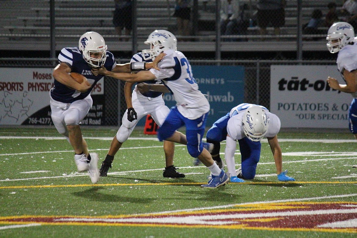 MLCA/CCS quarterback Ruben Uyanchuk (7) stiff-arms Soap Lake defender Grayson Pippens (33). The Lions defeated Soap Lake for their third straight win.