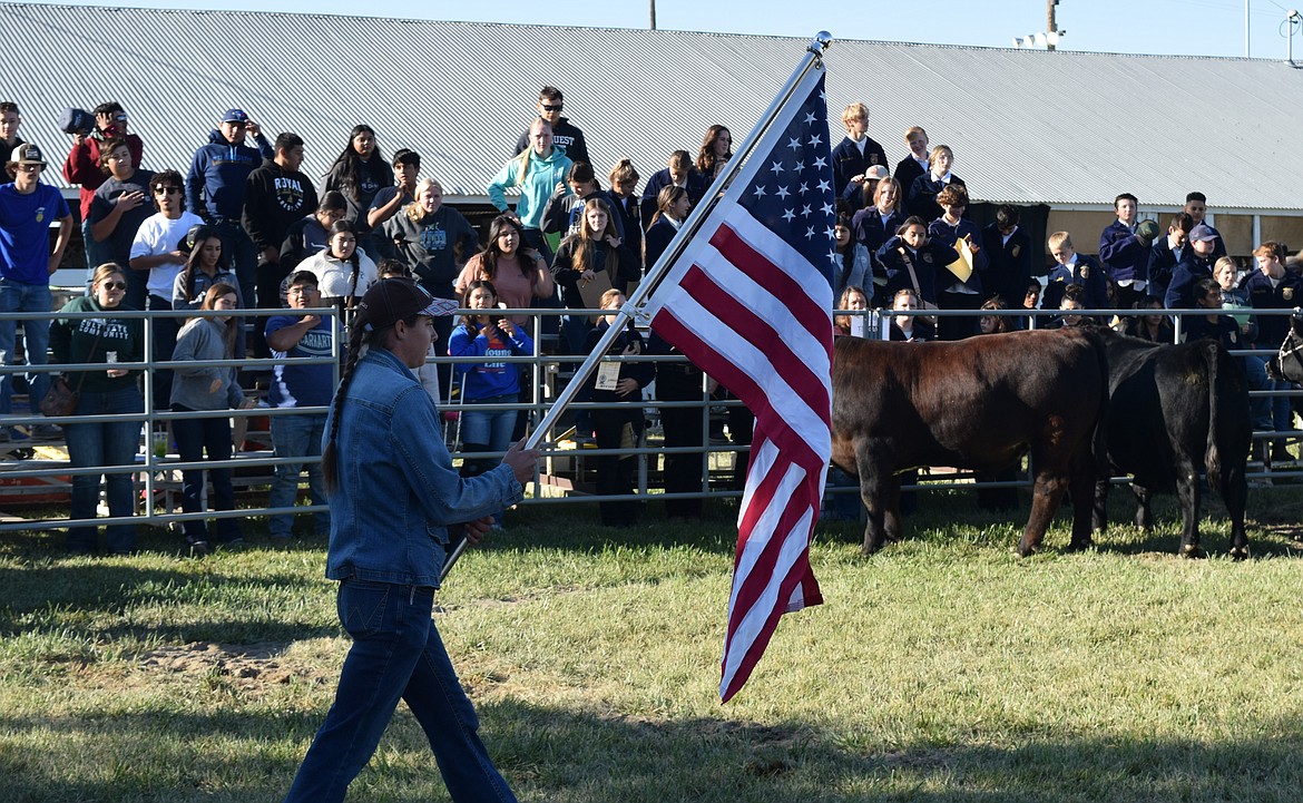 An event organizer presents the American flag while the national anthem plays at the start of the livestock judging competition Friday at the Othello Fair.