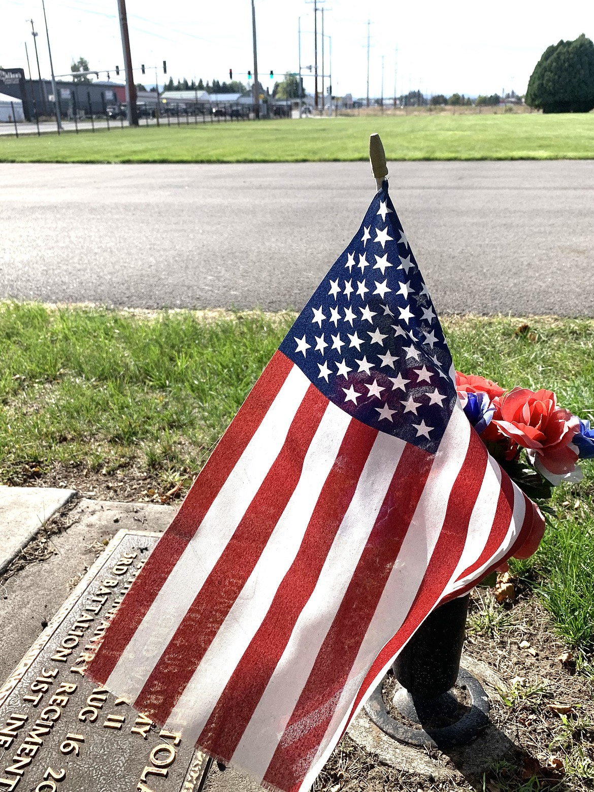 A flag flutters at Coeur d'Alene Memorial Gardens. Beyond the flag is the area designated for the Coeur d'Alene Gold Star Memorial Monument.