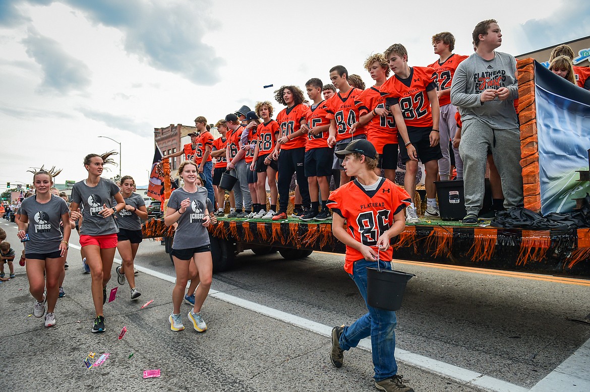 Members of the Braves JV football squad and runners from the cross country team hand out candy during the Flathead High School Homecoming Parade along Main Street in Kalispell on Wednesday, Sept. 20. (Casey Kreider/Daily Inter Lake)