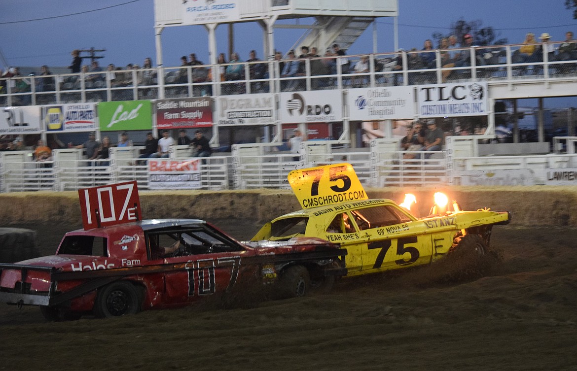 An Othello Demolition Derby competitor shoots flames from the front of his car as he and another competitor spin off the track during the heat races at the Sept. 13 event.