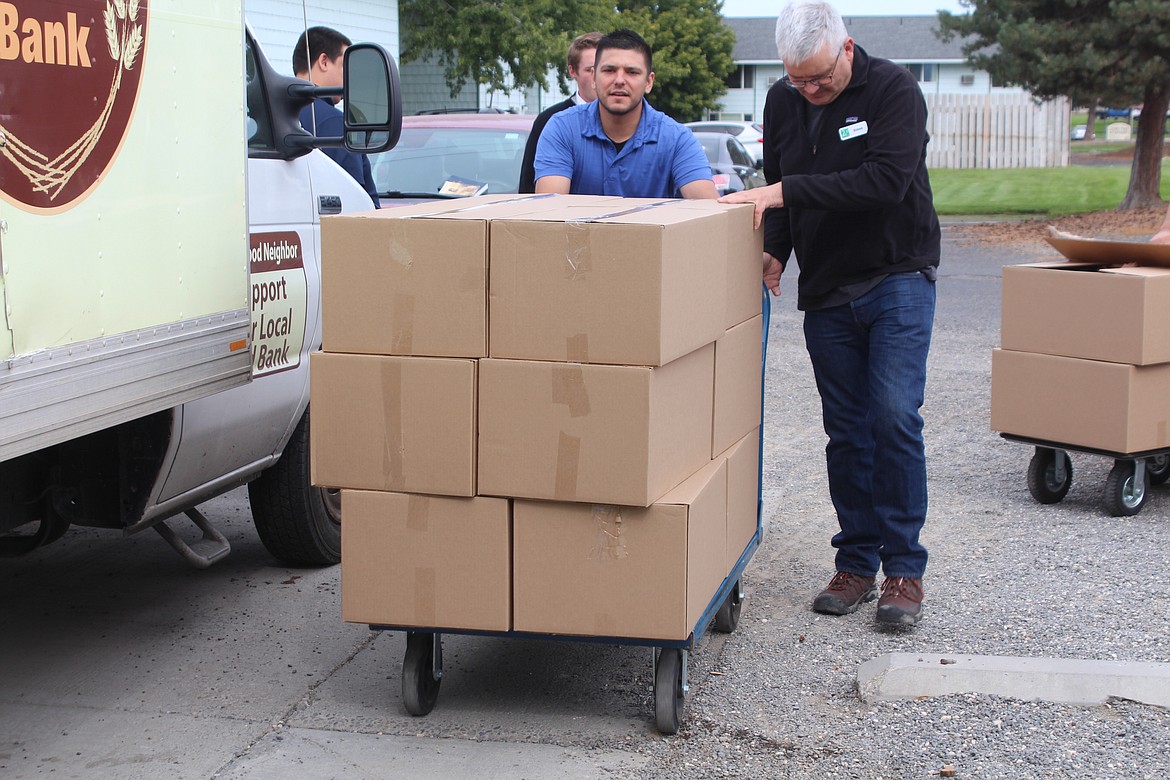 Jose Garza, left, Othello Food Bank director, and Steve Durham of 2nd Harvest wheel boxes of Bites 2 Go food sacks over to the truck for delivery to Othello elementary schools.