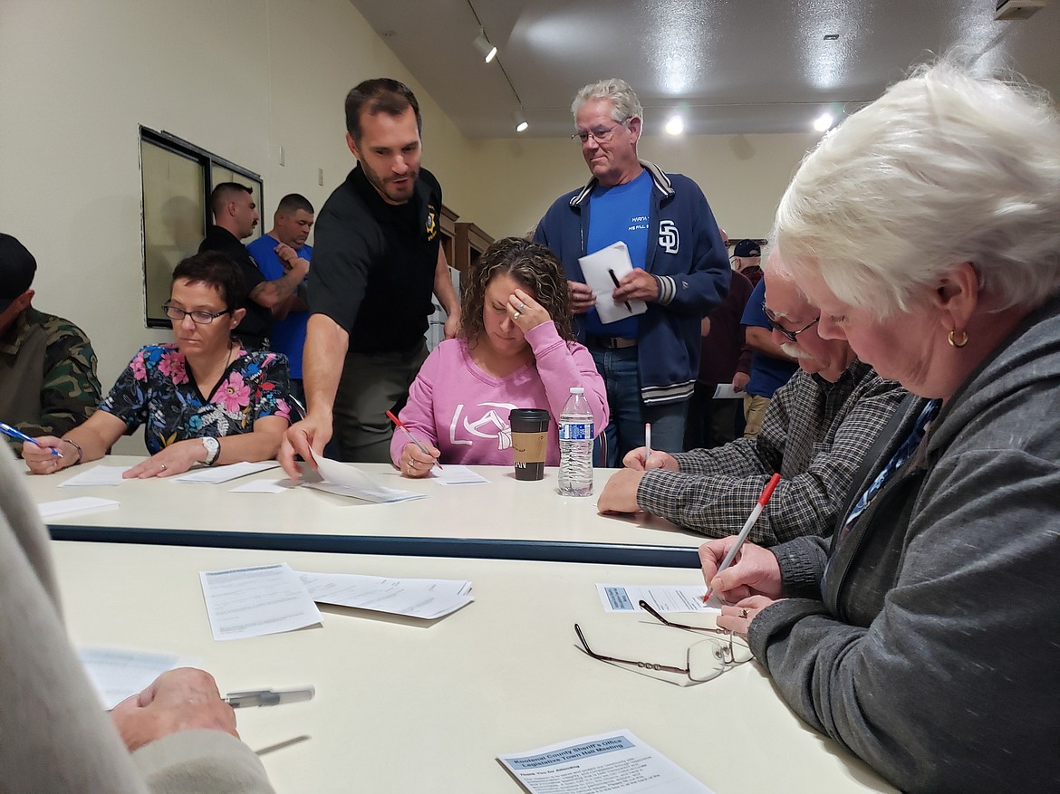 Center, Kootenai County resident Christie Peetoom takes a citizen survey while Lt. Mark Ellis (left) grabs a copy for John Scarborough (right). The survey results were announced in a town hall Thursday at the Hayden Eagles.