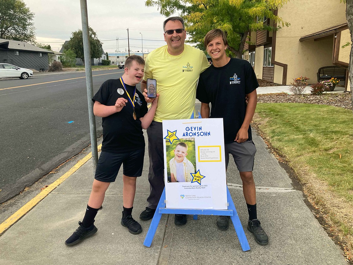 Gevin Aronsohn, left, poses for a photo at the Buddy Walk with his dad Eric Aronsohn and his brother Bryson Aronsohn.