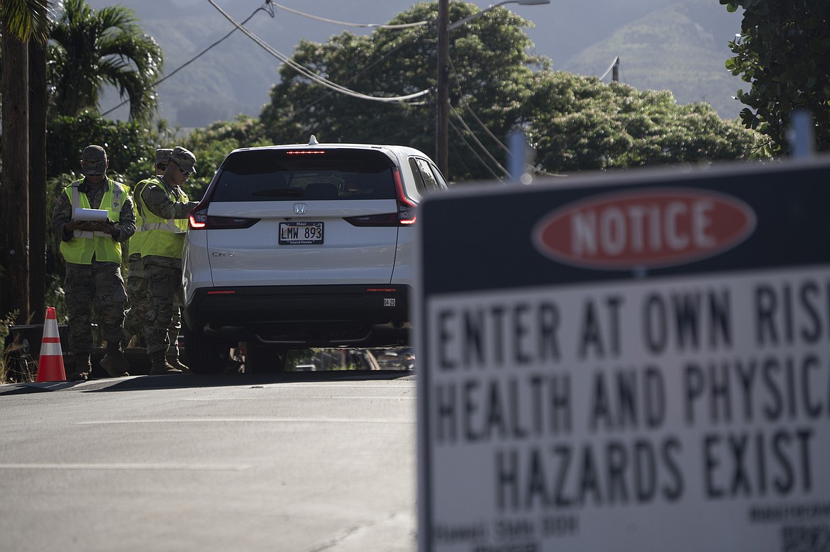 The Hawaii National Guard checks on a car passing the checkpoint on Kaniau Street on Monday, Sept. 25, 2023, in Lahaina, Hawaii. Kaniau Street of Zone 1C is the first zone to be cleared for re-entry starting today. (AP Photo/Mengshin Lin)