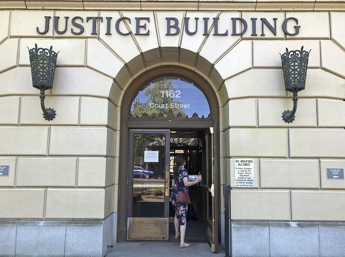 A woman enters the Oregon Department of Justice building in Salem, Ore., May 28, 2020. According to a ballot measure passed by Oregon voters, state senators who accumulated 10 or more unexcused absences at the Legislature during a record-setting Republican walkout are supposed to be disqualified from running for re-election, but several filed suit in the Oregon Court of Appeals, challenging the measure. On Monday, Sept. 25, 2023, the appeals court formally asked the state Supreme Court to handle the case. (AP Photo/Andrew Selsky, File)