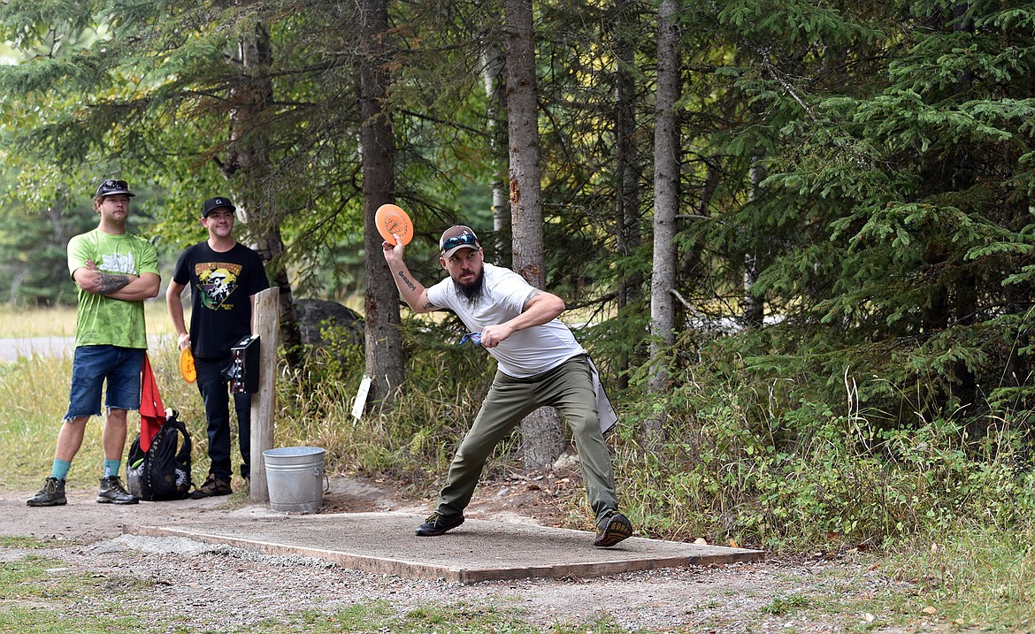 Disc golfer Ryan Dickey launches his tee shot while teammates Drew Boone and Joe Urban wait their turns. (Julie Engler/Whitefish Pilot)