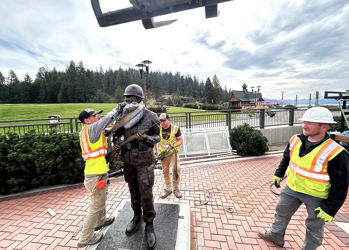 City workers from left, Richard Fortman, Will Worley and Cameron Poole finish putting a U.S. Army soldier bronze statue in place at McEuen Park Veterans Memorial Plaza.