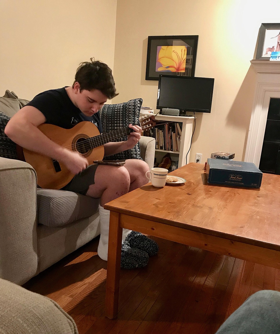 19-year-old Matthew Read plays guitar in his family's Michigan home while he makes his recovery from frostbite, which he contracted after being lost for several days in Glacier National Park this spring. (photo provided)