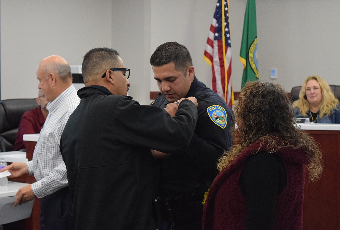 New Othello Police Officer Rene Sandoval’s father pins his medal to his chest while his mother watches during the Othello City Council meeting Monday evening.