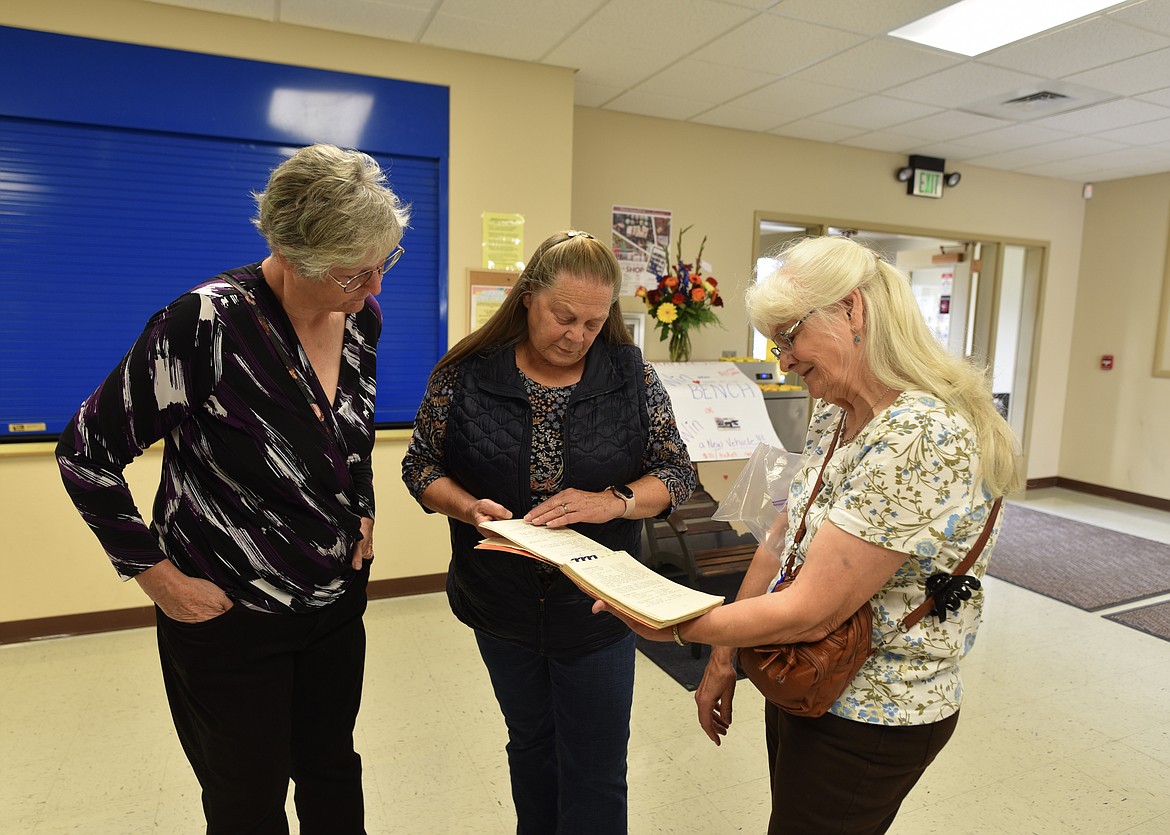 Former Cayuse Prairie School student Lois (Snell) Hook and former school clerk Linda Benson look at a "Cayuse Prairie Favorite Fixins" recipe book produced by the P&F Club. (Hilary Matheson/Daily Inter Lake)